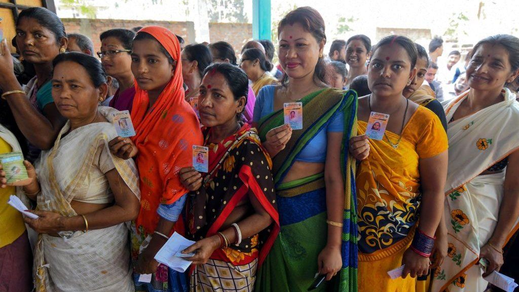 Indian voters show their voter identity cards as they stand in a queue to cast their vote at a polling station during India's general election in Samuguri village, some 140 km from Guwahati, the capital city of Indias northeastern state of Assam on April 11, 2019.