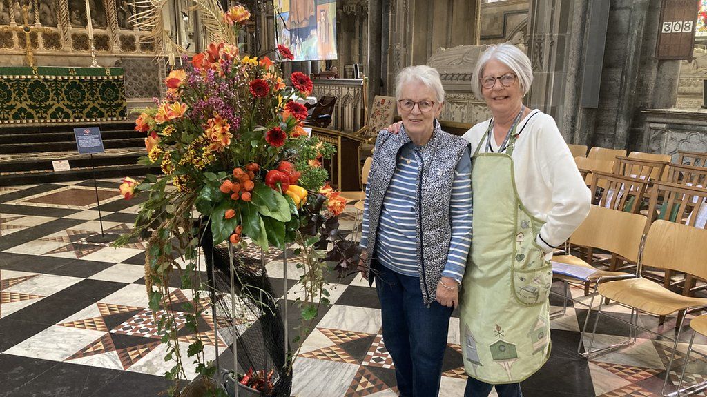 Judy Wynn and Mary Foister stood next to red and orange flower exhibition