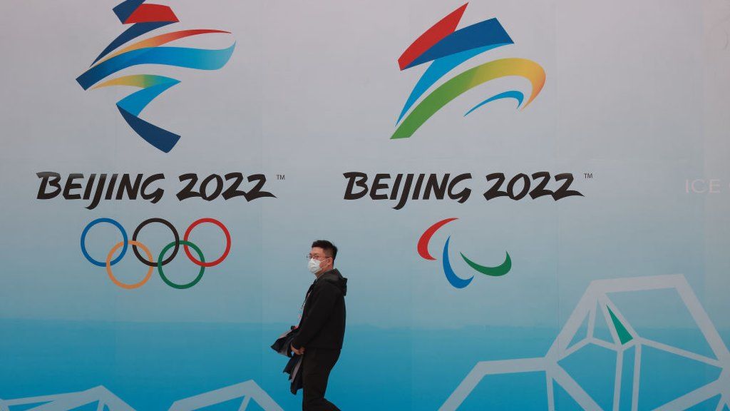 A man walks past a Beijing Olympics sign