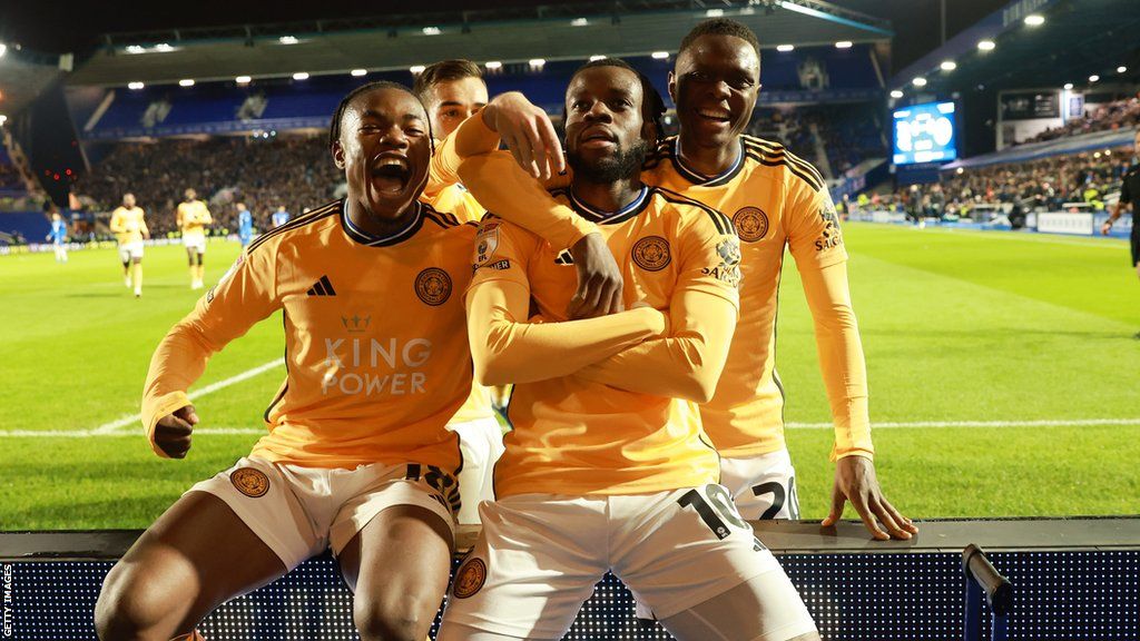 Stephy Mavididi with his arms crossed and team-mates around him as he sits on an advertising board at Birmingham to celebrate his first goal