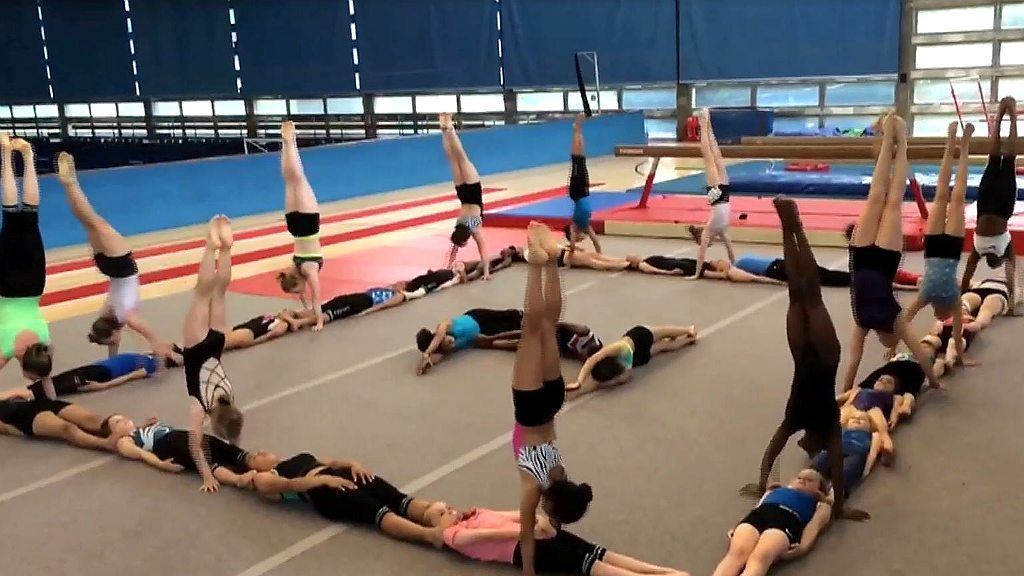 A gym club do synchronised handstands in a square