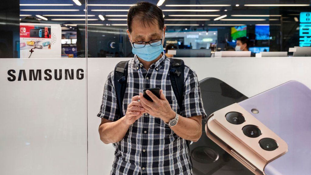 Мужчина стоит перед магазином по продаже телефонов Samsung в Гонконге.