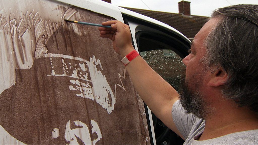 Artist Rick Minns painting on the side of his van