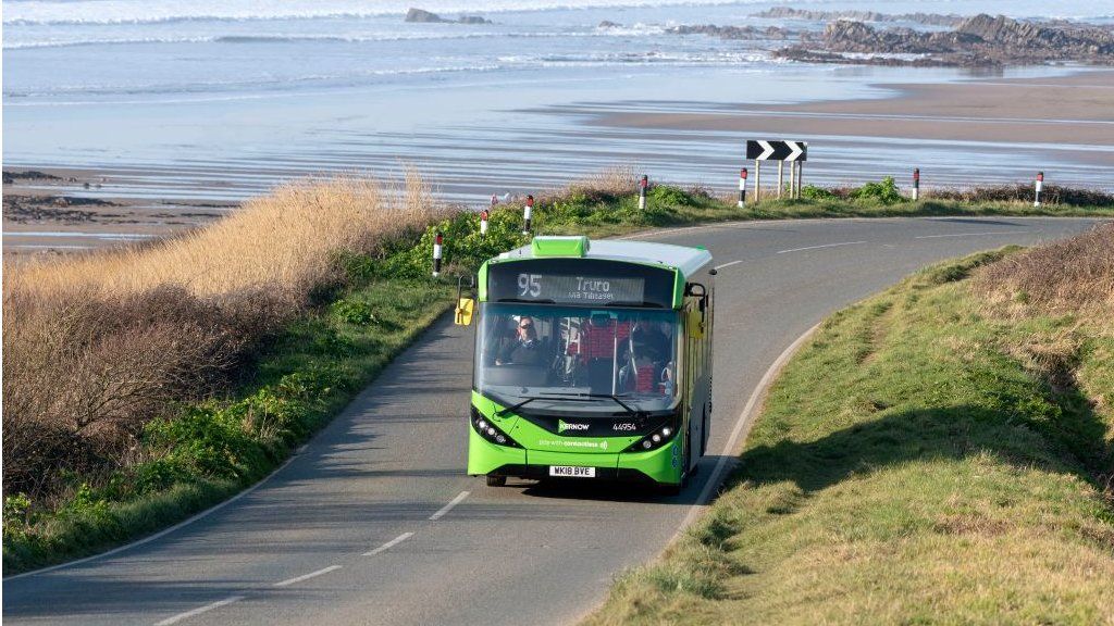 Single deck bus service at Widemouth Bay, close to Bude, north Cornwall with a backdrop of the sea