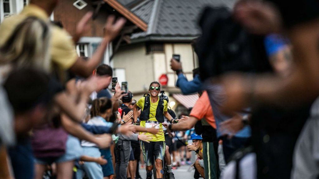 Courtney Dauwalter makes her way towards the finishline of the 2023 UTMB through a gauntlet of spectators