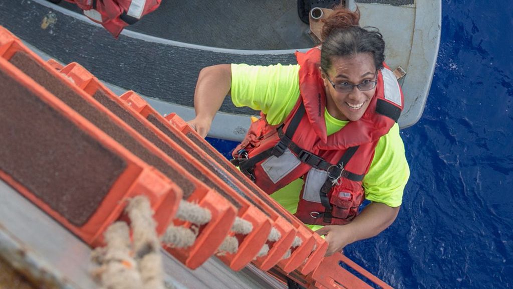 Tasha Fuiaba, a US mariner who had been sailing for five months on a damaged sailboat, climbing on board the USS Ashland in the Pacific Ocean, 25 October 2017