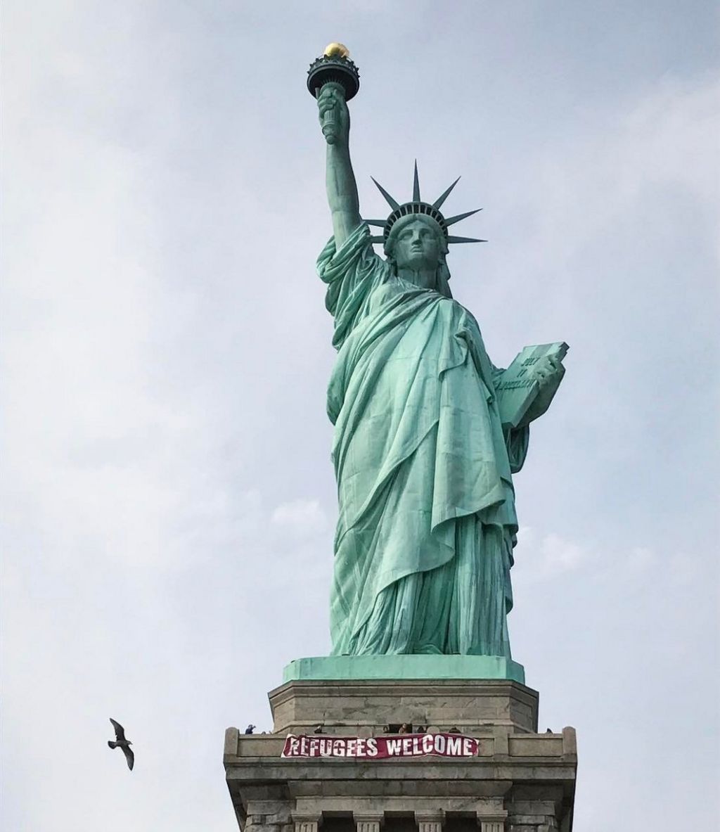 A giant banner saying "Refugees Welcome" hangs on the pedestal of the Statue of Liberty, New York, 21 February 2017