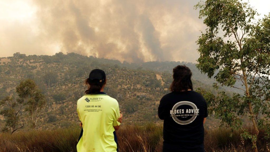 People look on as a fire driven by strong winds burns on a ridge in the suburb of Brigadoon in Perth on 2 February 2021, forcing emergency evacuations just days after the west coast city entered a coronavirus lockdown