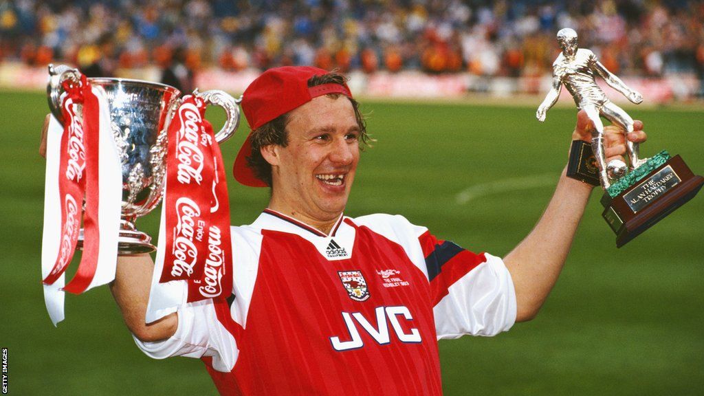 Paul Merson holds trophies while at Arsenal
