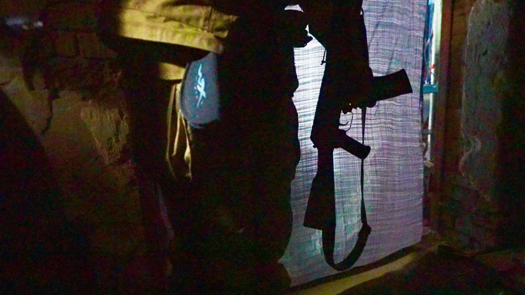 Darkened room, a Ukrainian soldier holds a weapon