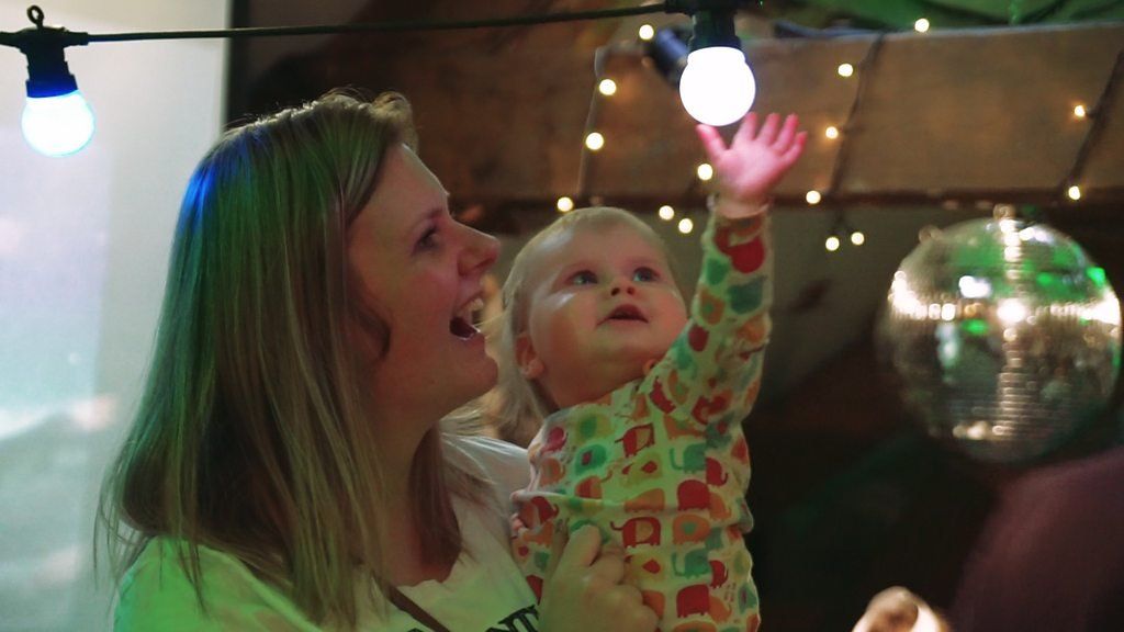 A baby looks up at fairy lights