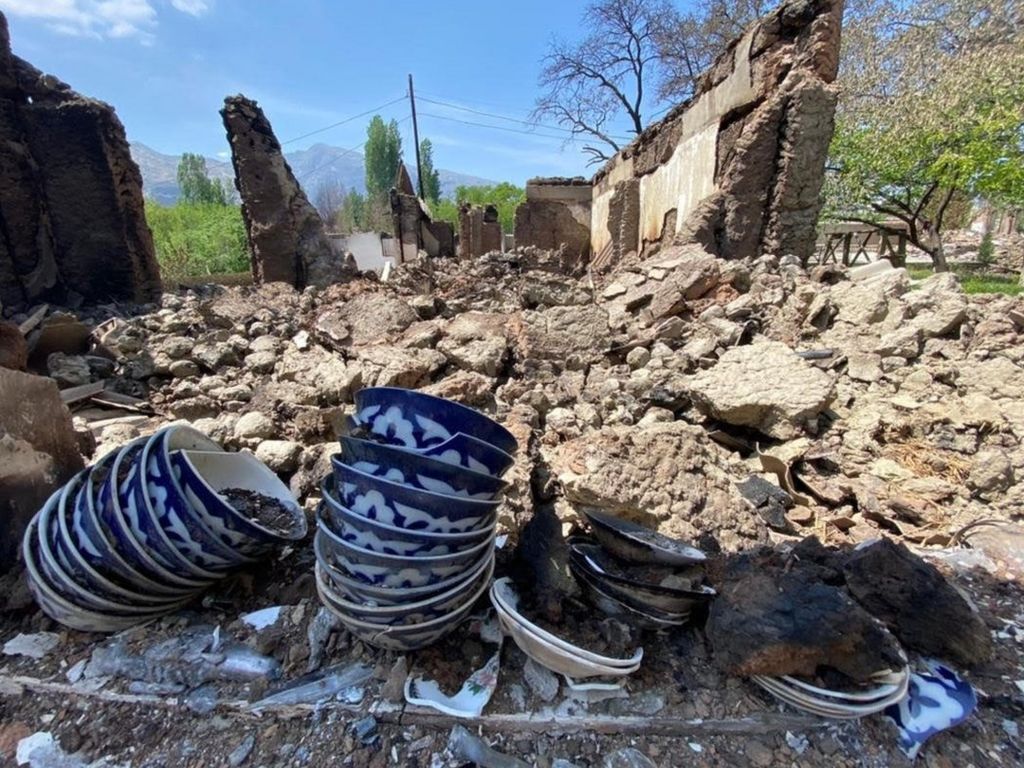 Some crockery is displayed near a home that has been reduced to rubble