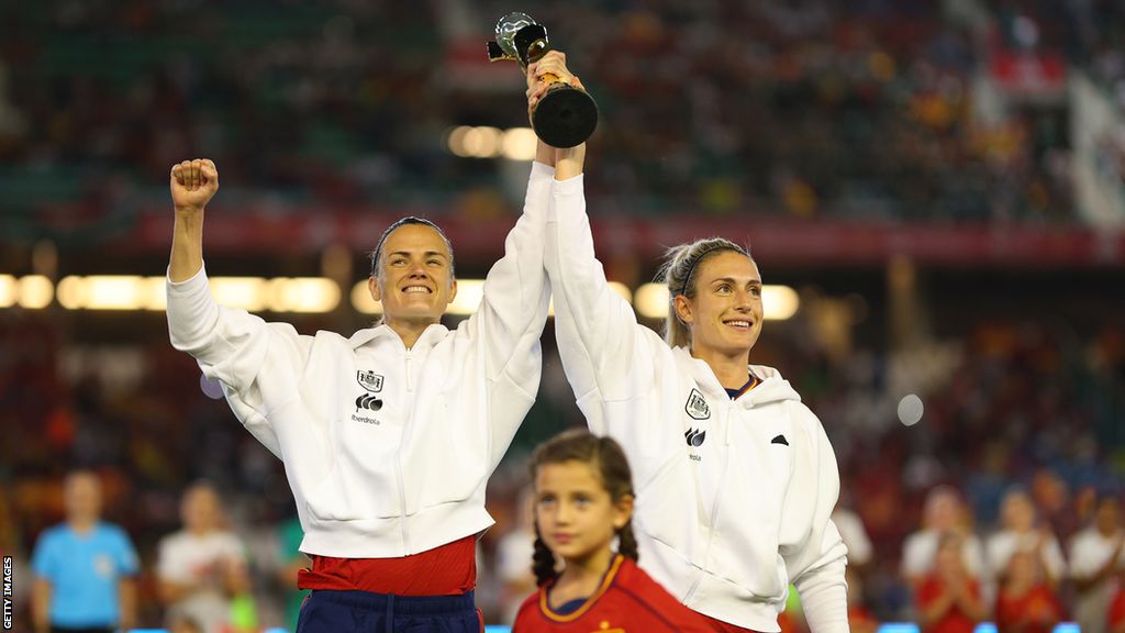 Irene Paredes of Spain and Alexia Putellas show off the World Cup trophy before kick-off against Switzerland