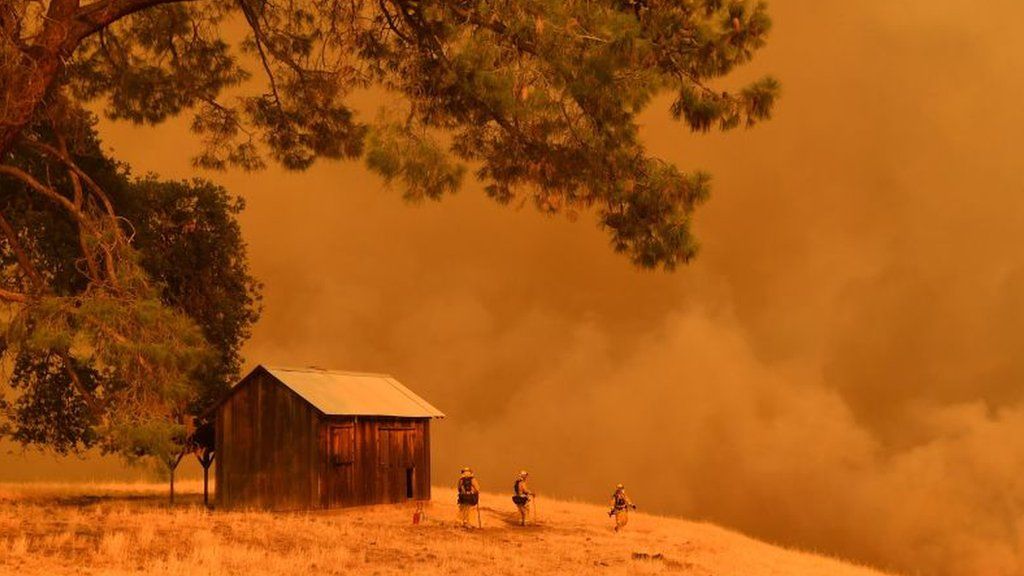 Firefighters ward off a blaze near a barn in a remote California valley