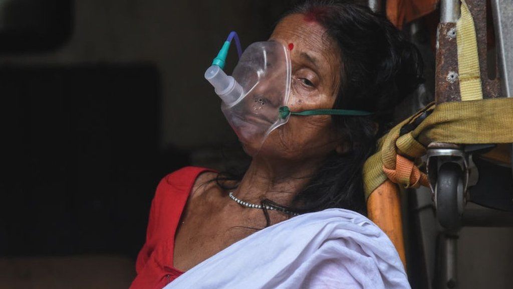 An elderly woman with breathing difficulty inhales medication with the help of nebuliser or oxygen mask, inside an ambulance, at MMCH hospital in Guwahati, Assam, India on 25 May 2021.