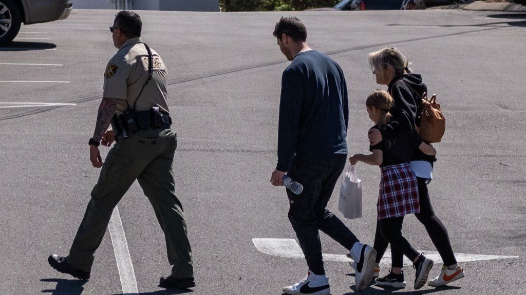 A law enforcement officer escorts a family from a church where children were reunited with their families