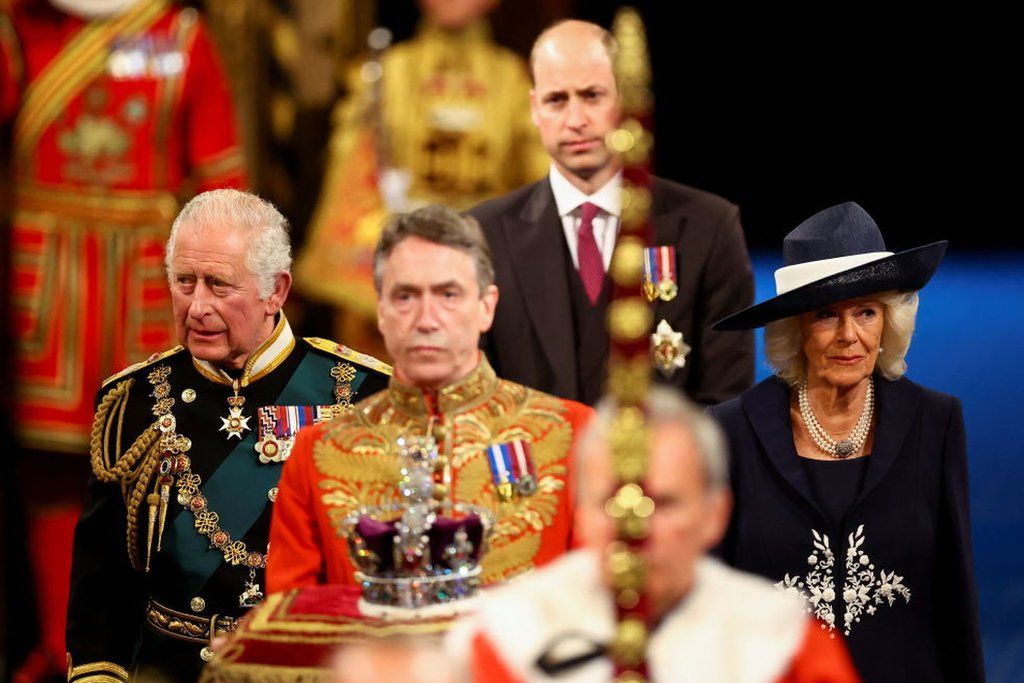 Prince Charles, Prince of Wales, Camilla, Duchess of Cornwall and Prince William proceed behind the Imperial State Crown through the Royal Gallery for the State Opening of Parliament in the House of Lords at the Palace of Westminster on 10 May 2022