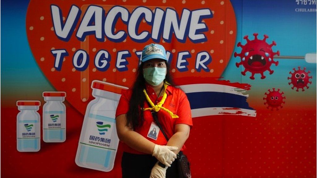 A Thai health volunteer stands in front of a campaign banner for Chinese made Sinopharm vaccine during a mass vaccination drive for disabled and disadvantaged people in Bangkok, Thailand, 25 June 2021.