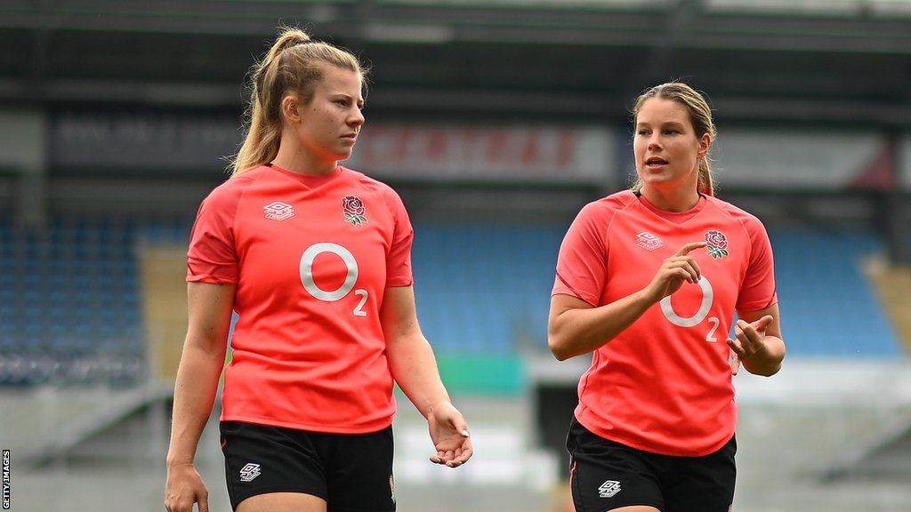 Zoe Harrison (left) and Jess Breach walk on the pitch during warm-up before an England match
