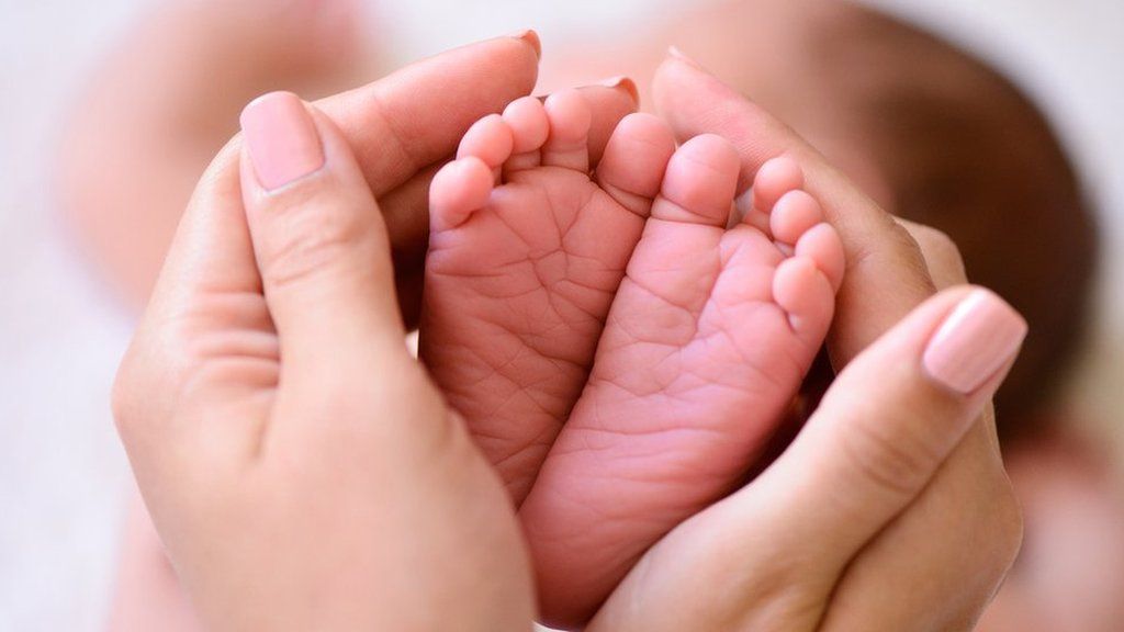 Adult's hands around a baby's feet