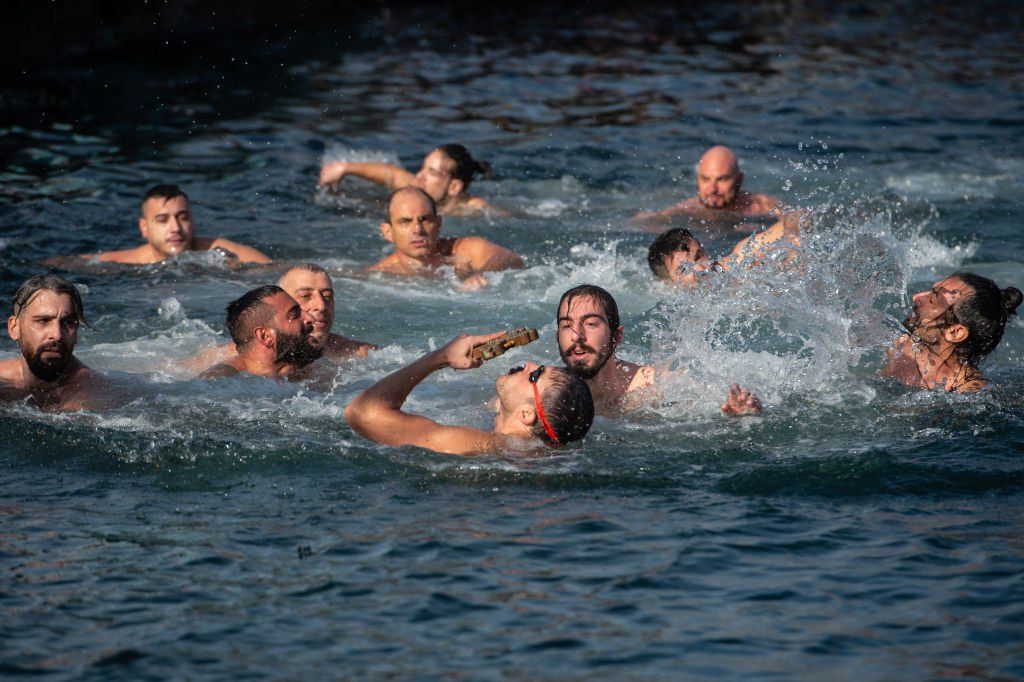 Greek Orthodox faithful Galip Yavuz, holds up a wooden cross