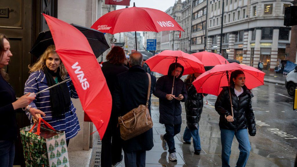 Public on a London street holding umbrellas