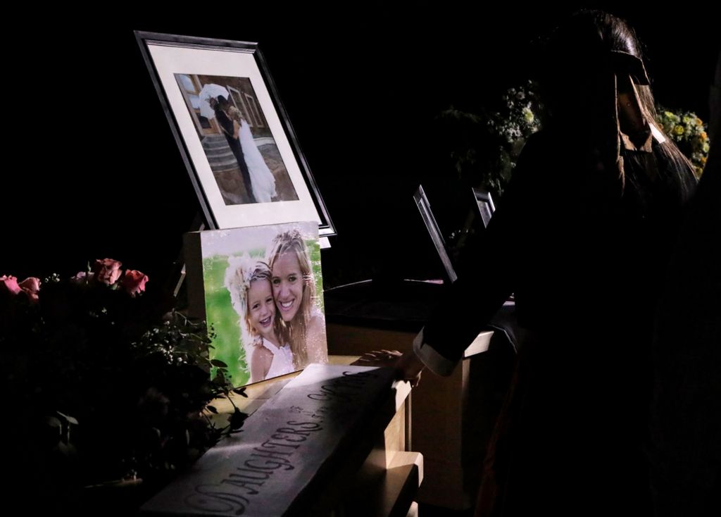 A girl looks at the coffins with the remains of Rhonita Miller and four of her children