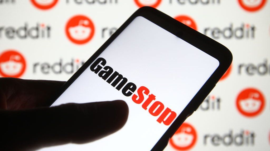 GameStop logo on a phone against a background of Reddit logos.