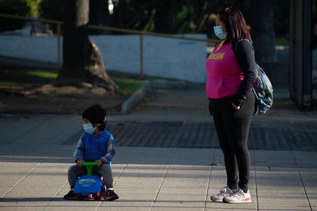 Мальчик в своей игрушечной машине и его мать гуляют по улицам Сантьяго, 13 мая, Сантьяго, Чили.