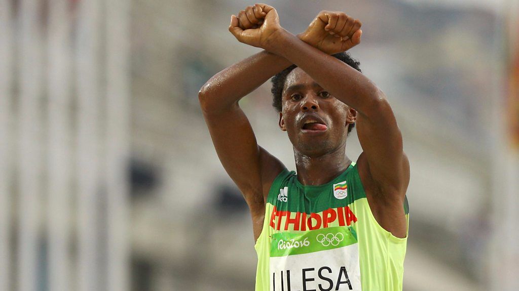 Feyisa Lilesa crosses finish line with arms making an x sign