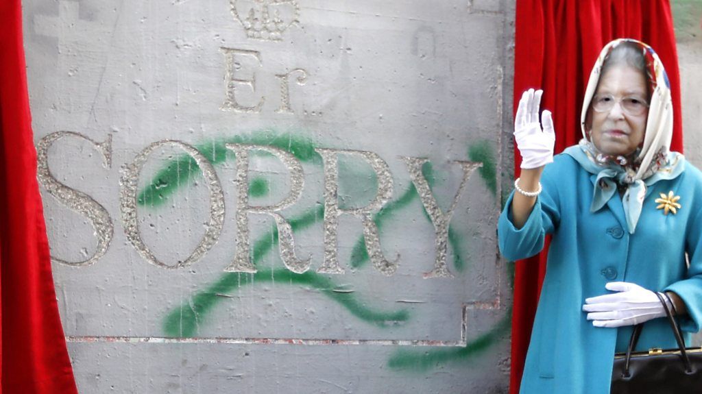 Actor dressed as the Queen in front of Banksy's carving