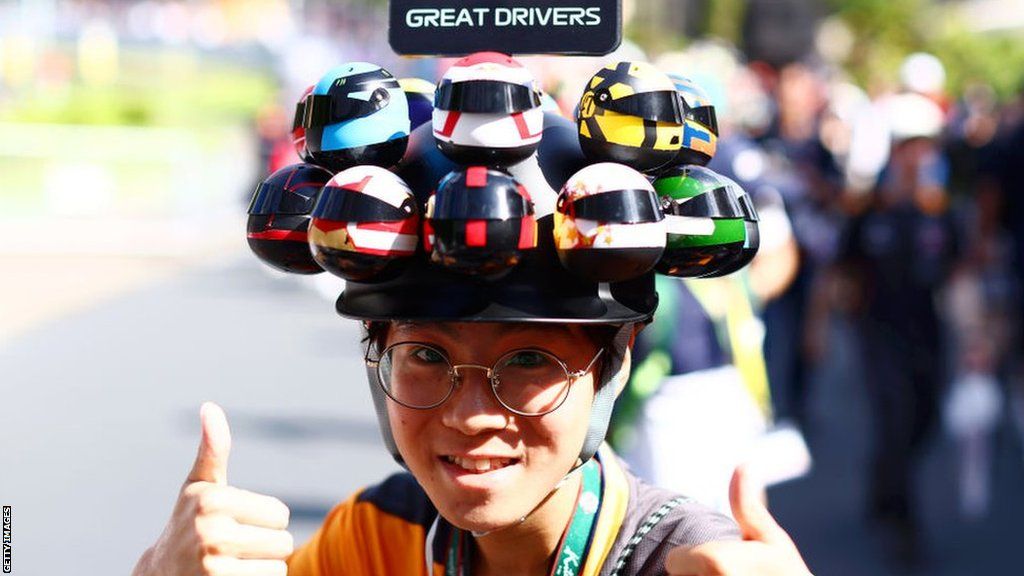 A fan poses with a hat made of mini driver helmets at the Japanese Grand Prix in Suzuka