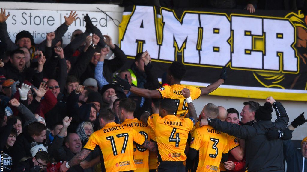 Newport County player Shawn McCoulsky celebrates his winning goal with fans and team mates during The Emirates FA Cup Third Round match between Newport County and Leeds United at Rodney Parade on January 7, 2018 in Newport, Wales.