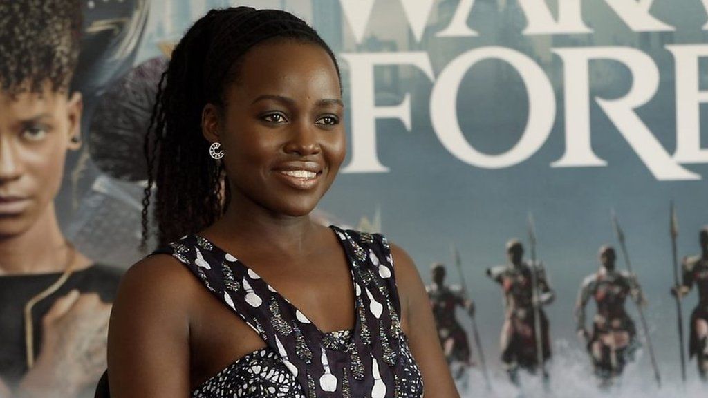 Lupita Nyong’o in front of Black Panther; Wakanda Forever poster