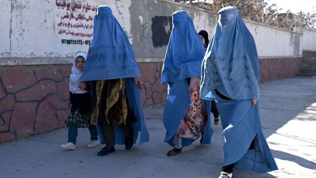 Women in Islamic veils walk along a road in Ghazni Province, Afghanistan