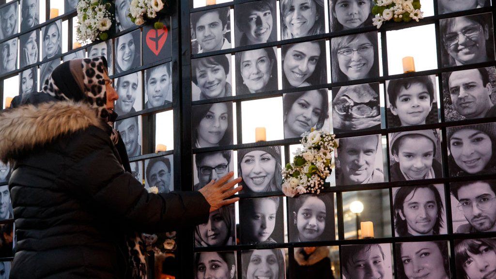 Photo of woman at Toronto memorial in 2022 overlooking photos of some victims of Flight 752.