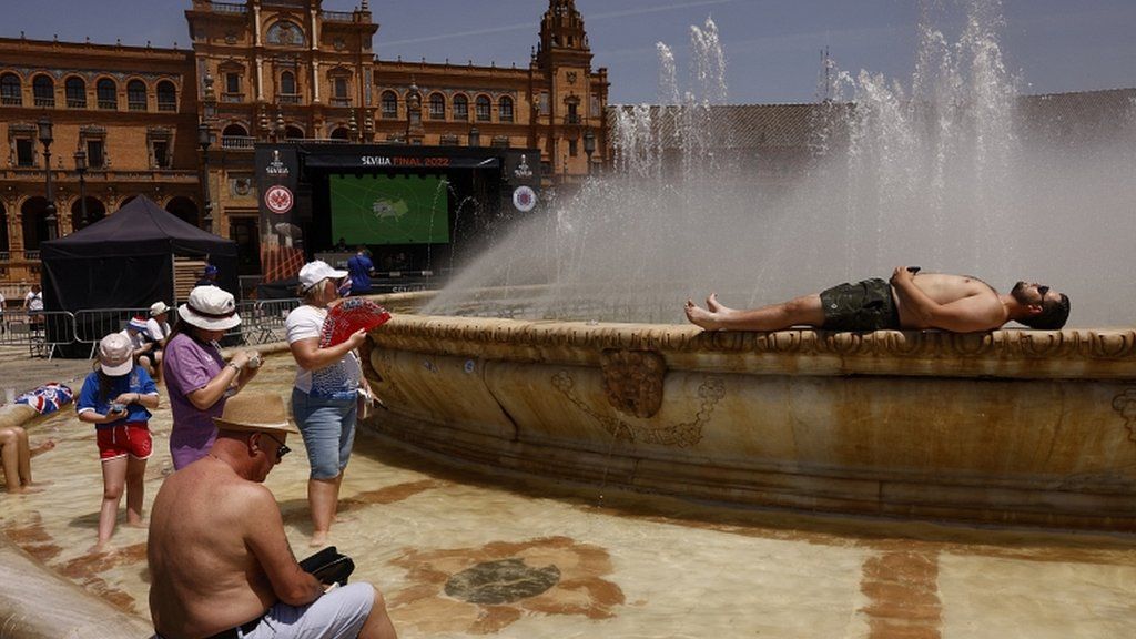 A shirtless fan lies on the side of a fountain in one of the fan zones
