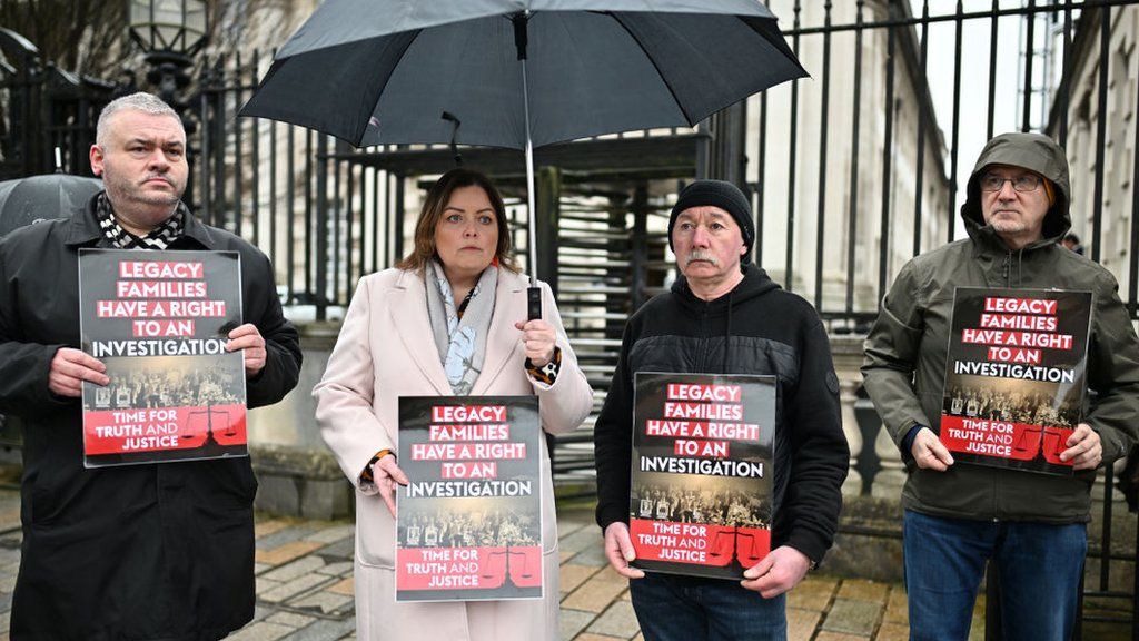 BELFAST, NORTHERN IRELAND - FEBRUARY 28: Supporters of Troubles victims hold placards outside the High Court ahead of the court ruling on February 28, 2024 in Belfast, Northern Ireland.