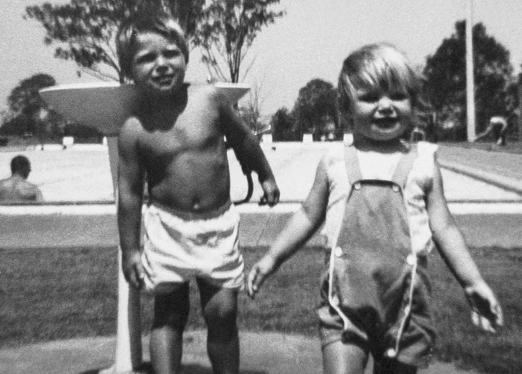 Cheryl with one of her brothers by a swimming pool water fountain