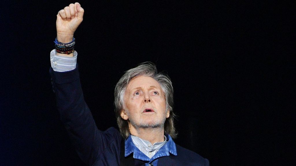 Paul McCartney raises his hand to the air during a concert at the O2 Arena in December 2024