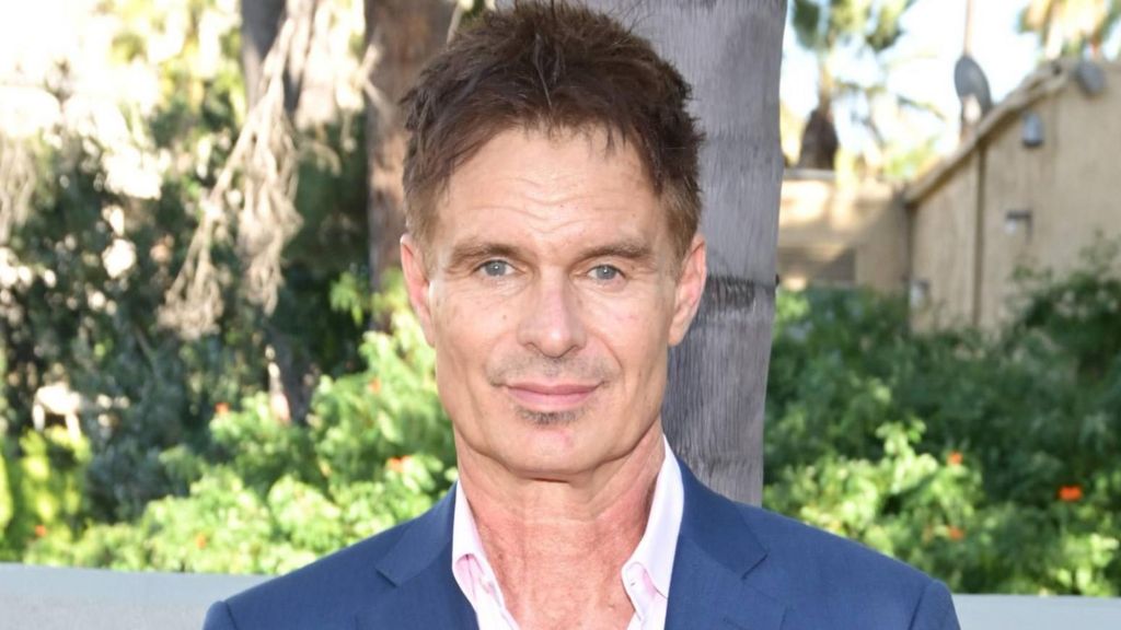 Patrick Muldoon wearing a white open-necked shirt and blue suit jacket