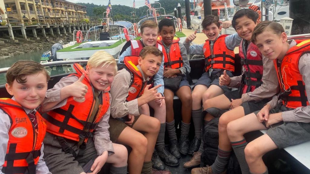 Eight boys in lifejackets on a boat
