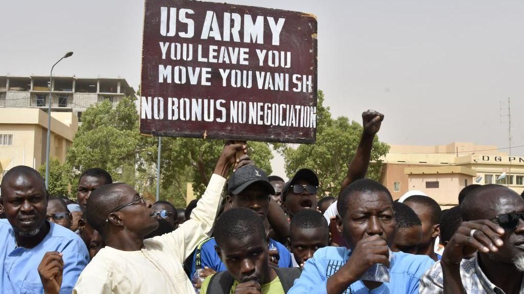 Protesters react as a man holds up a sign demanding that soldiers from the United States Army leave Niger without negotiation during a demonstration in Niamey, on April 13, 2024
