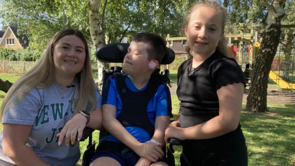 A child in a wheelchair with two other children in a garden