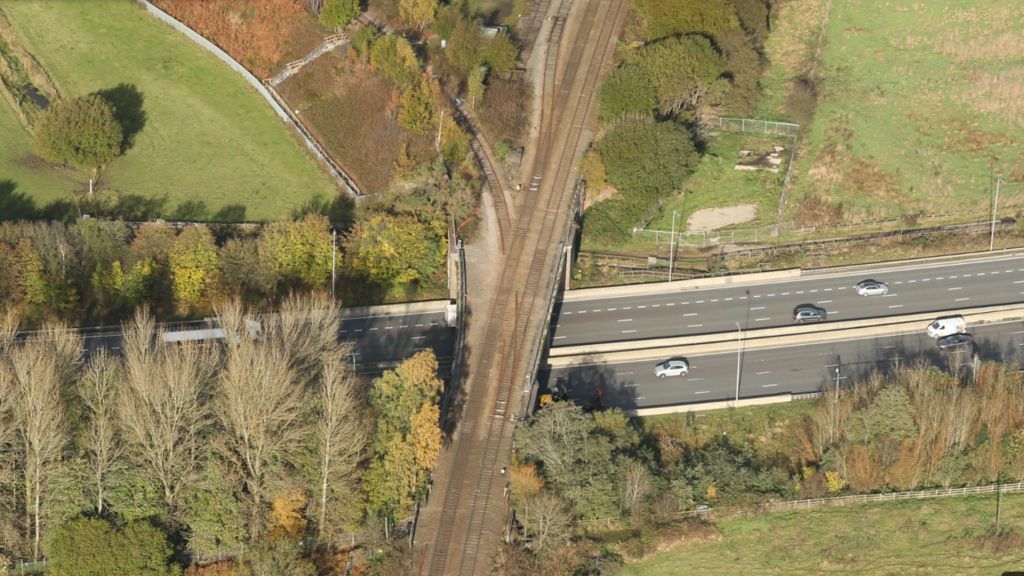 An aerial view picture of a bridge going across a motorway. 