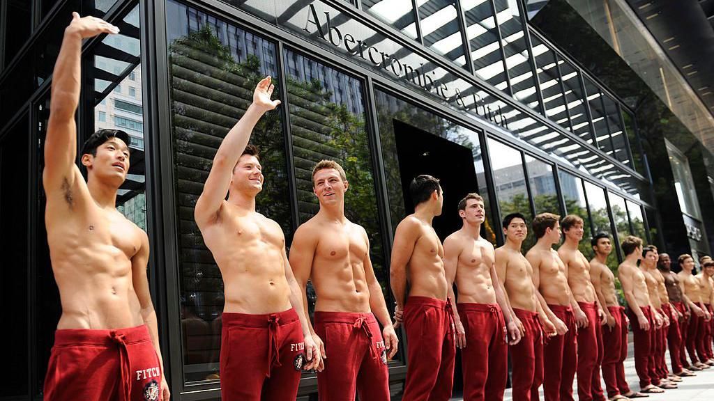 Abercrombie & Fitch (A&F) models beckon the public to take pictures with them outside the A&F store in Knightsbridge, a Singapore shopping mall on December 9, 2011.