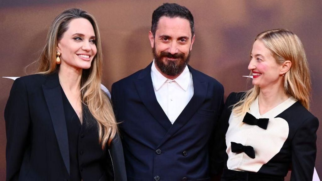 (L-R) Angelina Jolie with director Pablo Larraín and co-star Alba Rohrwacher. All three are smiling.