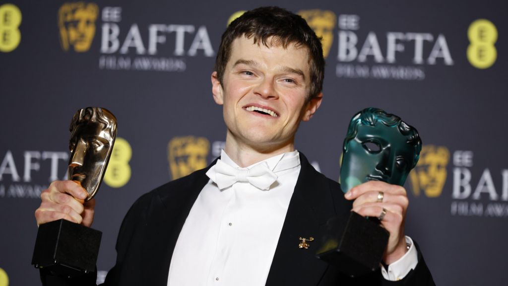 Robert Aramayo holding up two Bafta trophies