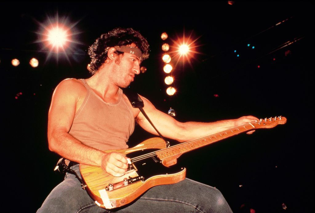 Bruce Springsteen poses with a guitar, while playing on stage in the 1980s