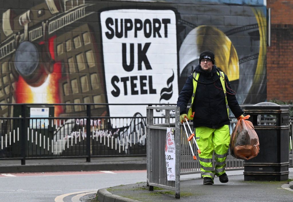 A rubbish collector walks past a mural in support of the UK Steel near to the Port Talbot steelworks